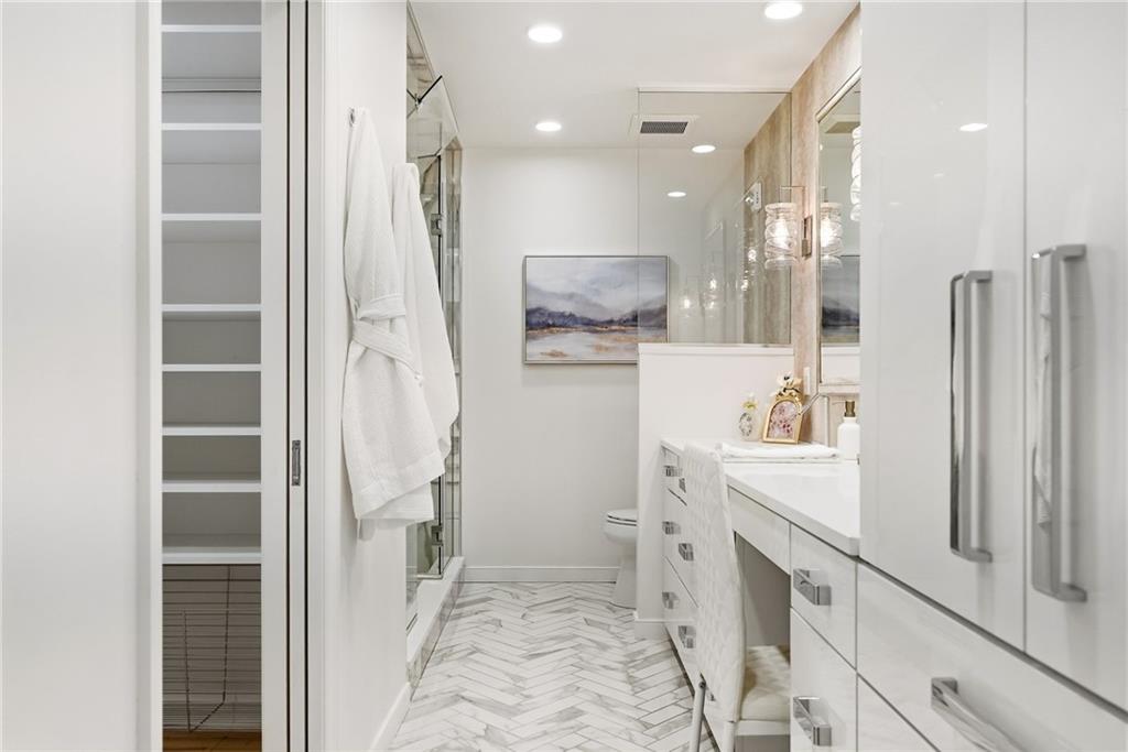5742 Fifth Avenue, Unit 304 Pittsburgh, PA 15232 - Photo 19 of 32 a bathroom with a double vanity sink a toilet a glass door a shower and a mirror