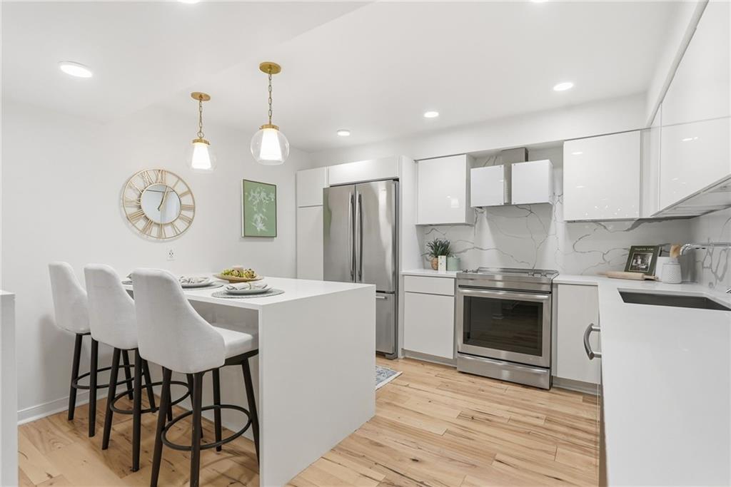 5742 Fifth Avenue, Unit 304 Pittsburgh, PA 15232 - Photo 3 of 32 a kitchen with stainless steel appliances granite countertop a stove a sink dishwasher a dining table and chairs with wooden floor
