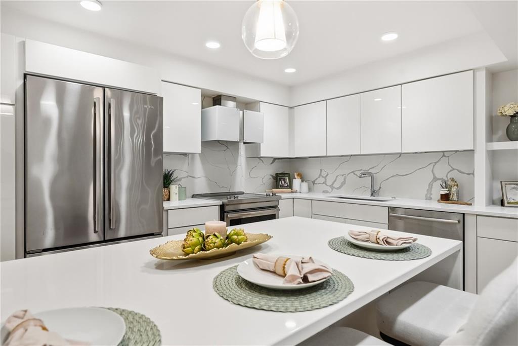 5742 Fifth Avenue, Unit 304 Pittsburgh, PA 15232 - Photo 5 of 32 a kitchen with stainless steel appliances a table and chairs in it