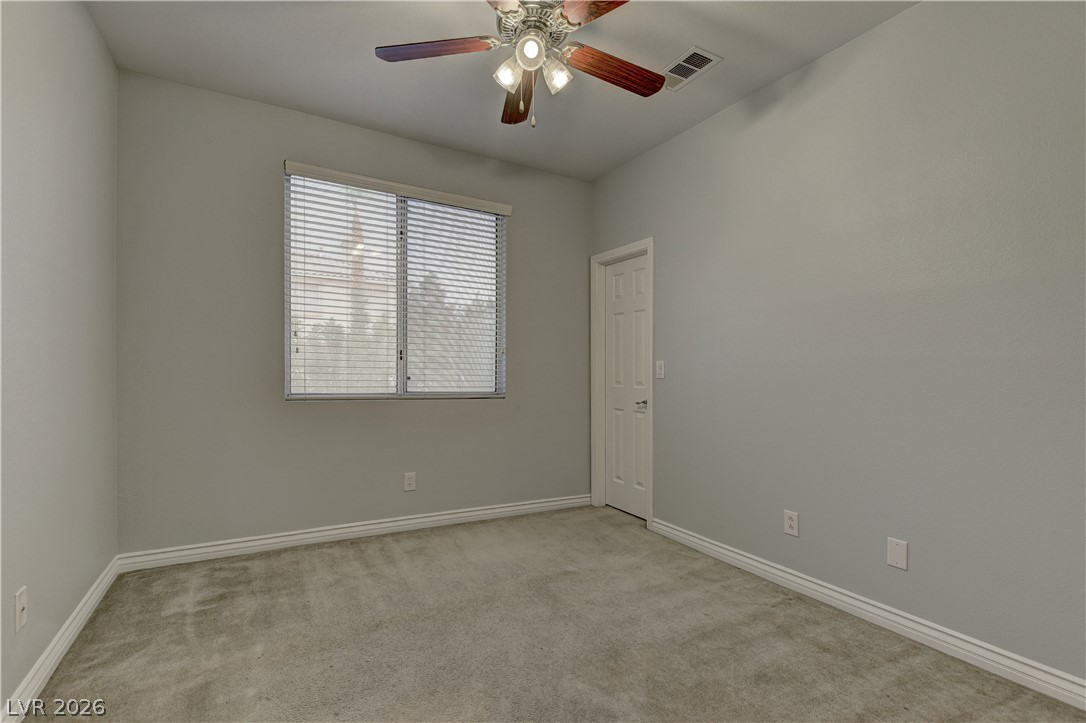 1813 Snow Spring Lane Las Vegas, NV 89134 - Photo 29 of 37 A well-lit bedroom features plush carpeting and a ceiling fan, offering a comfortable retreat.