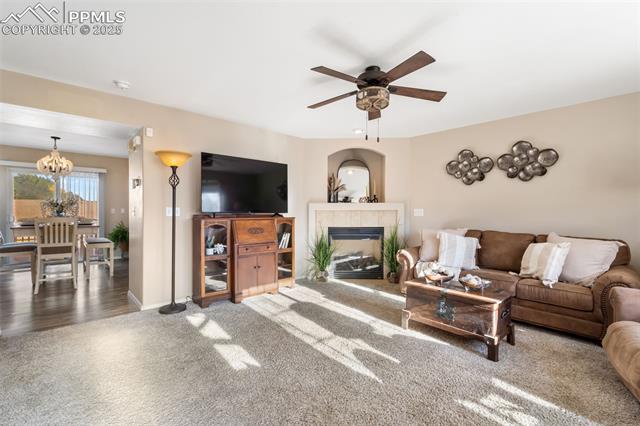 712 Rye Ridge Road Fountain, CO 80817 - Photo 11 of 45 Carpeted living room featuring ceiling fan, a fireplace, and a chandelier