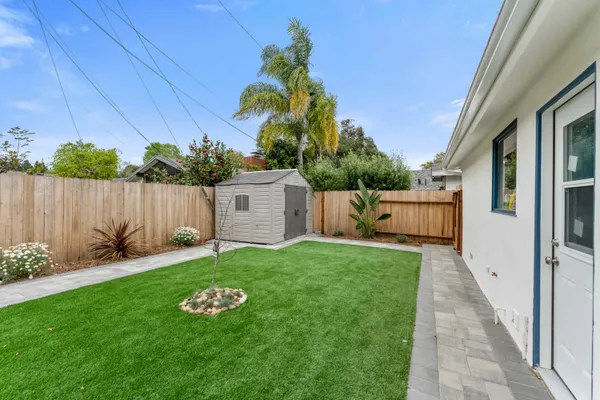 a view of a house with a yard and large tree