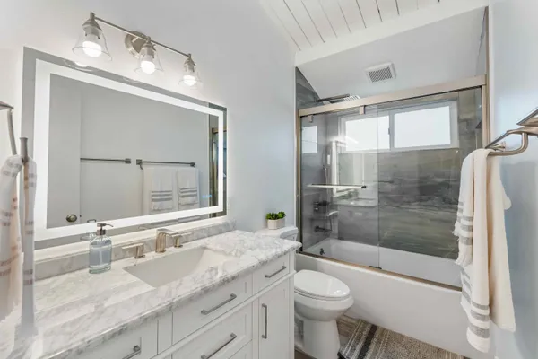 a bathroom with a granite countertop sink toilet mirror and bathtub
