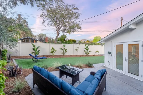 a view of a backyard with couches table and chairs and potted plants