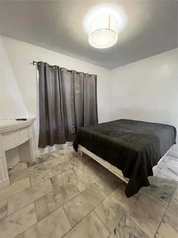 a bed sitting in a bedroom next to a window and a chair