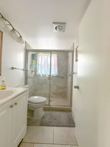 a bathroom with a granite countertop sink a toilet and a shower