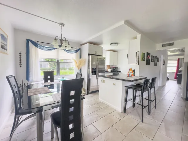 a kitchen with stainless steel appliances kitchen island granite countertop a dining table chairs and granite counter tops