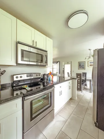 a kitchen with a stove a microwave and white cabinets