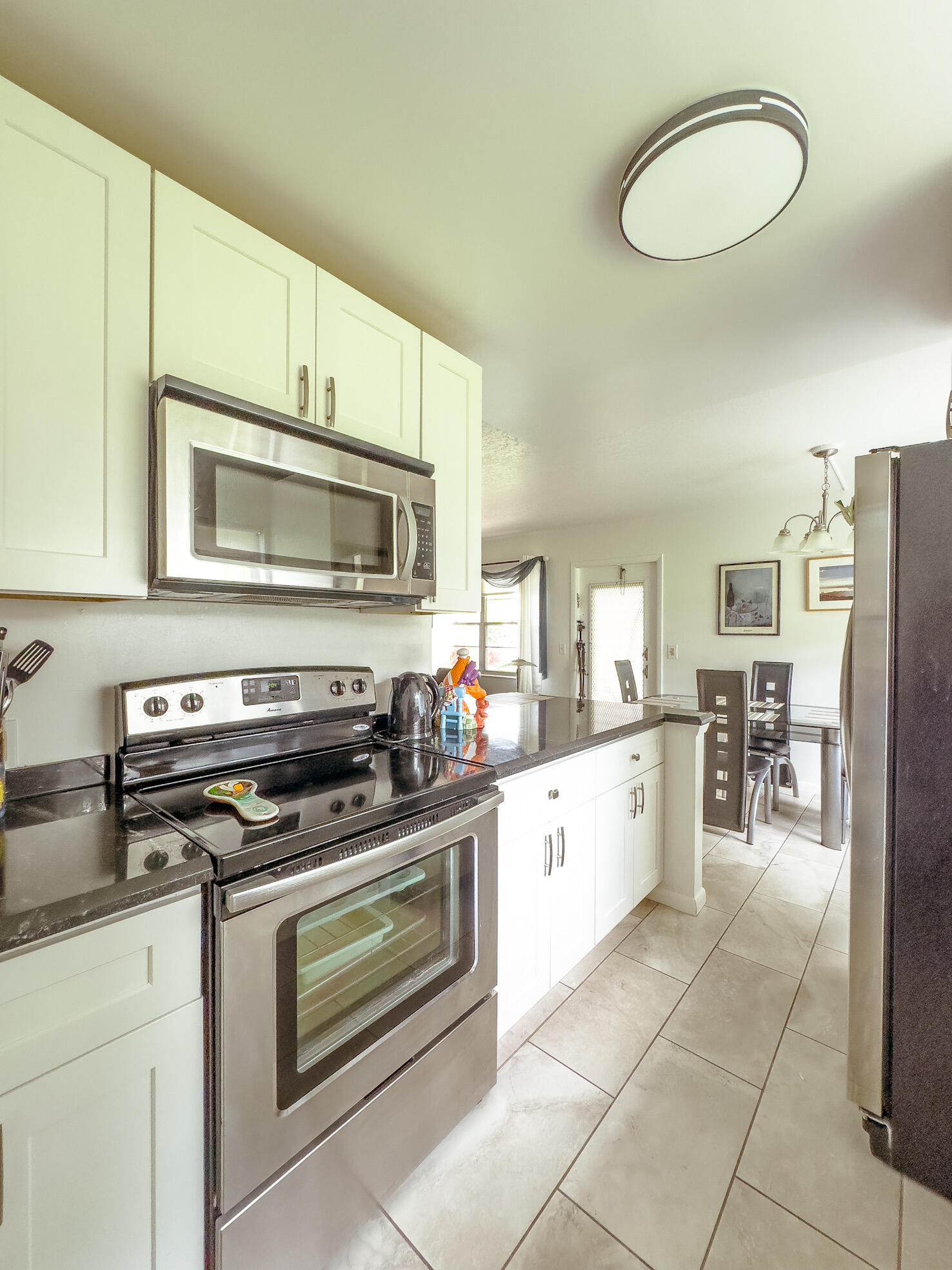 127 Mansfield D Boca Raton, FL 33434 - Photo 9 of 27 a kitchen with a stove a microwave and white cabinets