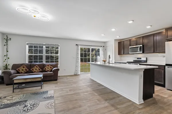 a living room with stainless steel appliances kitchen island granite countertop a couch and a large window