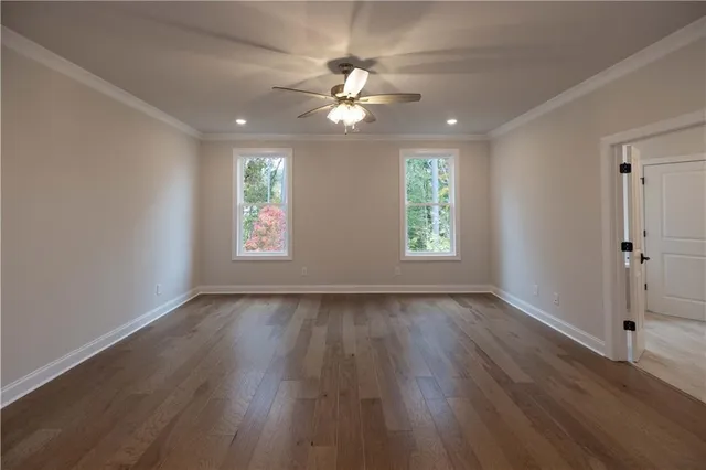 an empty room with wooden floor and a ceiling fan
