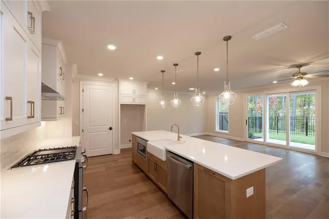 a large kitchen with kitchen island a sink stainless steel appliances and a large window