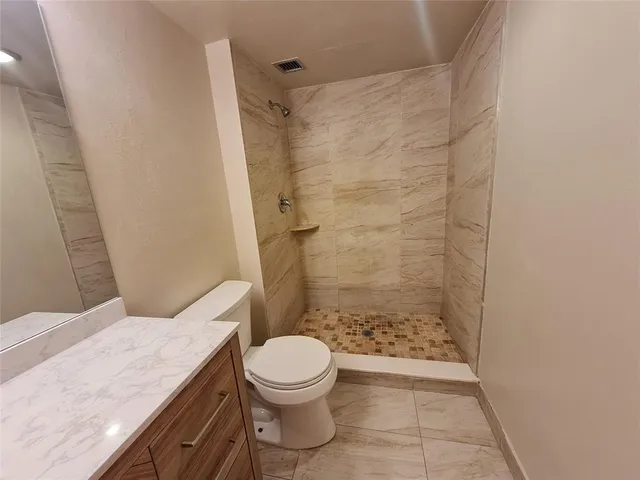 a bathroom with a granite countertop toilet a sink and shower