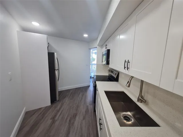 a kitchen with a refrigerator and a stove top oven