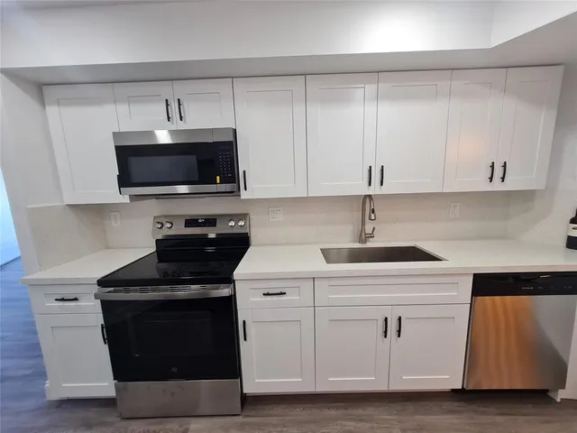 a kitchen with white cabinets and black appliances
