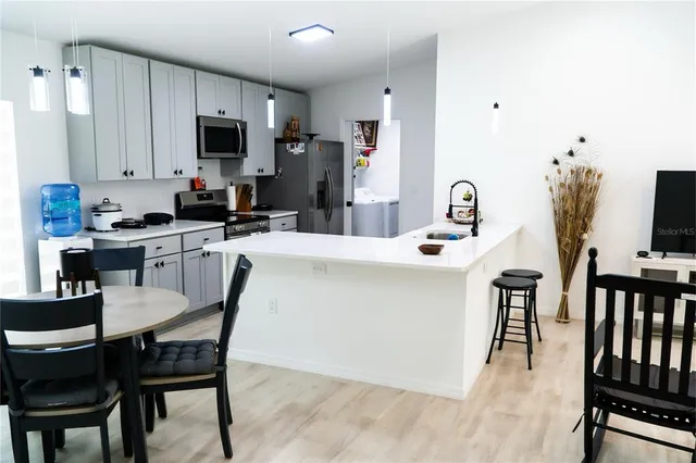 a kitchen with kitchen island a dining table chairs stainless steel appliances and cabinets