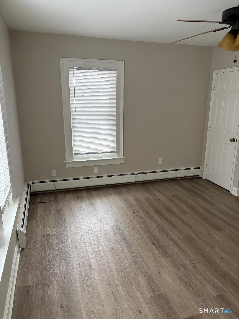 65 Ingraham Street, Unit 2 Bristol, CT 06010 - Photo 9 of 11 an empty room with wooden floor and windows