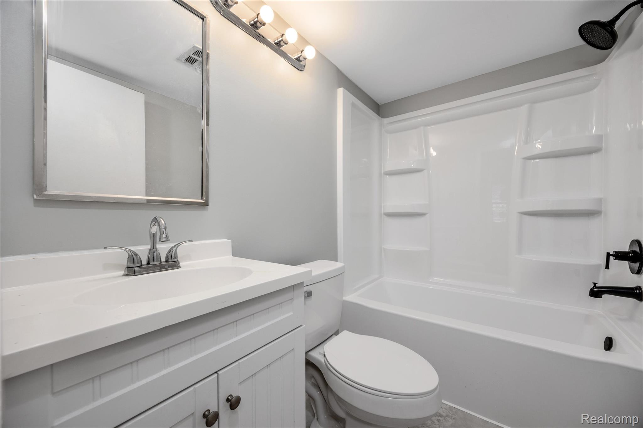 4942 Butler Drive Troy, MI 48085 - Photo 20 of 33 Bathroom featuring a white vanity with integrated sink, chrome faucet, framed mirror, and a white tub/shower combination with black fixtures