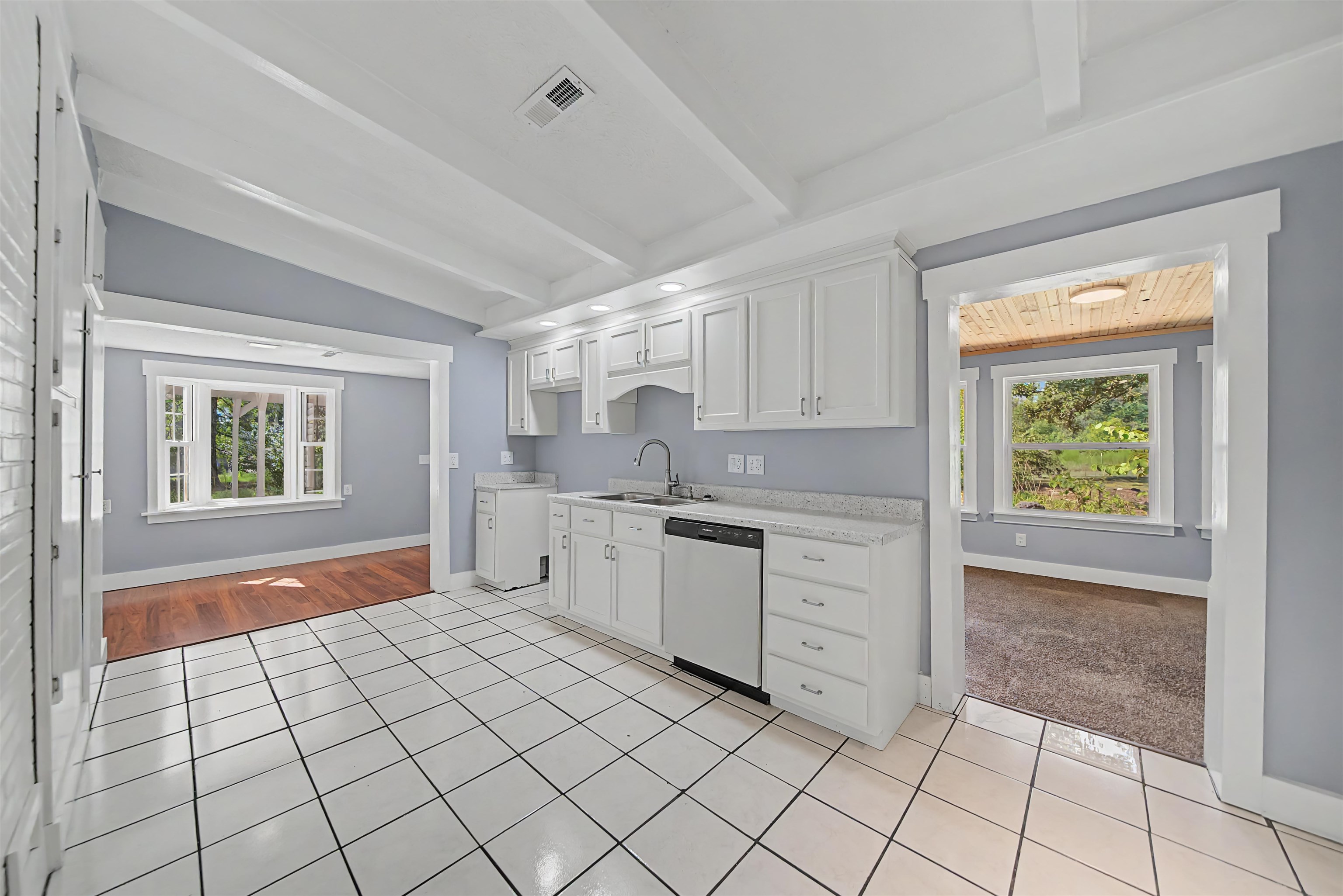 7437 Highway 45 Ramer, TN 38367 - Photo 17 of 36 White tile flooring, white shaker cabinetry, light-toned countertops, vaulted ceiling with exposed beams, and a built-in dishwasher