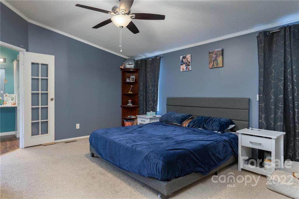 2776 Devine Road Iron Station, NC 28080 - Photo 10 of 23 a bedroom with a large bed and a chandelier