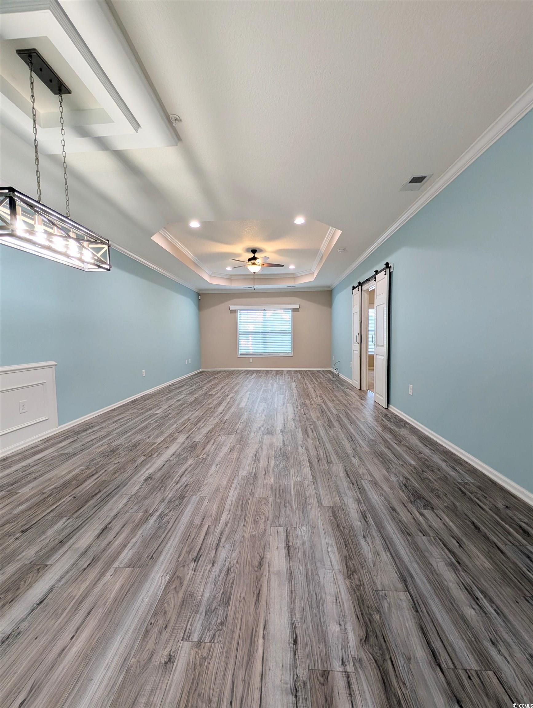 822 Sail Lane Murrells Inlet, SC 29576 - Photo 11 of 34 Unfurnished room featuring a barn door, a tray ceiling, crown molding, wood finished floors, and ceiling fan
