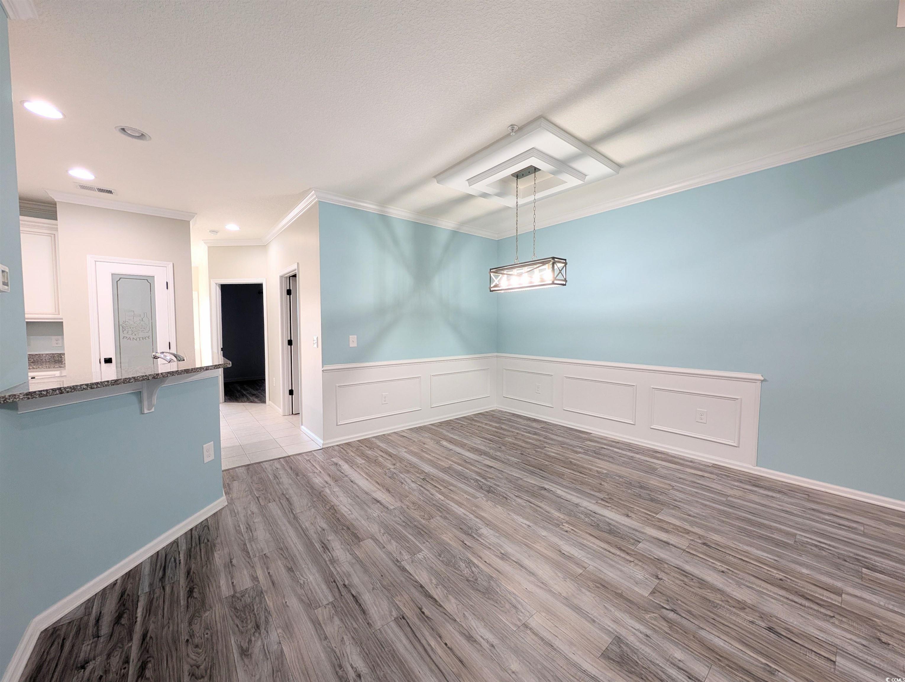 822 Sail Lane Murrells Inlet, SC 29576 - Photo 13 of 34 Unfurnished dining area featuring a wainscoted wall, light wood finished floors, crown molding, and a decorative wall