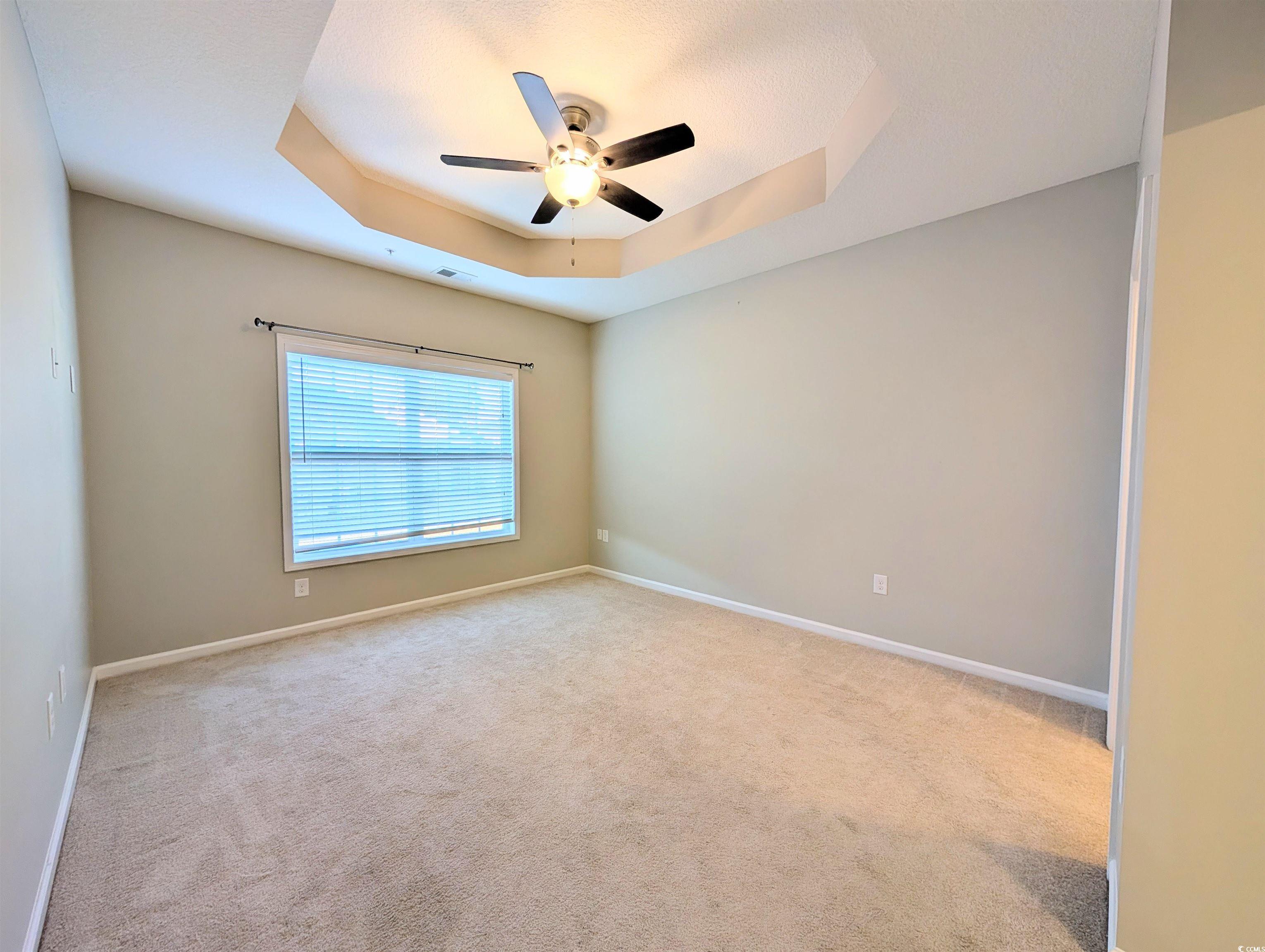 822 Sail Lane Murrells Inlet, SC 29576 - Photo 15 of 34 Spare room featuring a tray ceiling, light carpet, and a ceiling fan