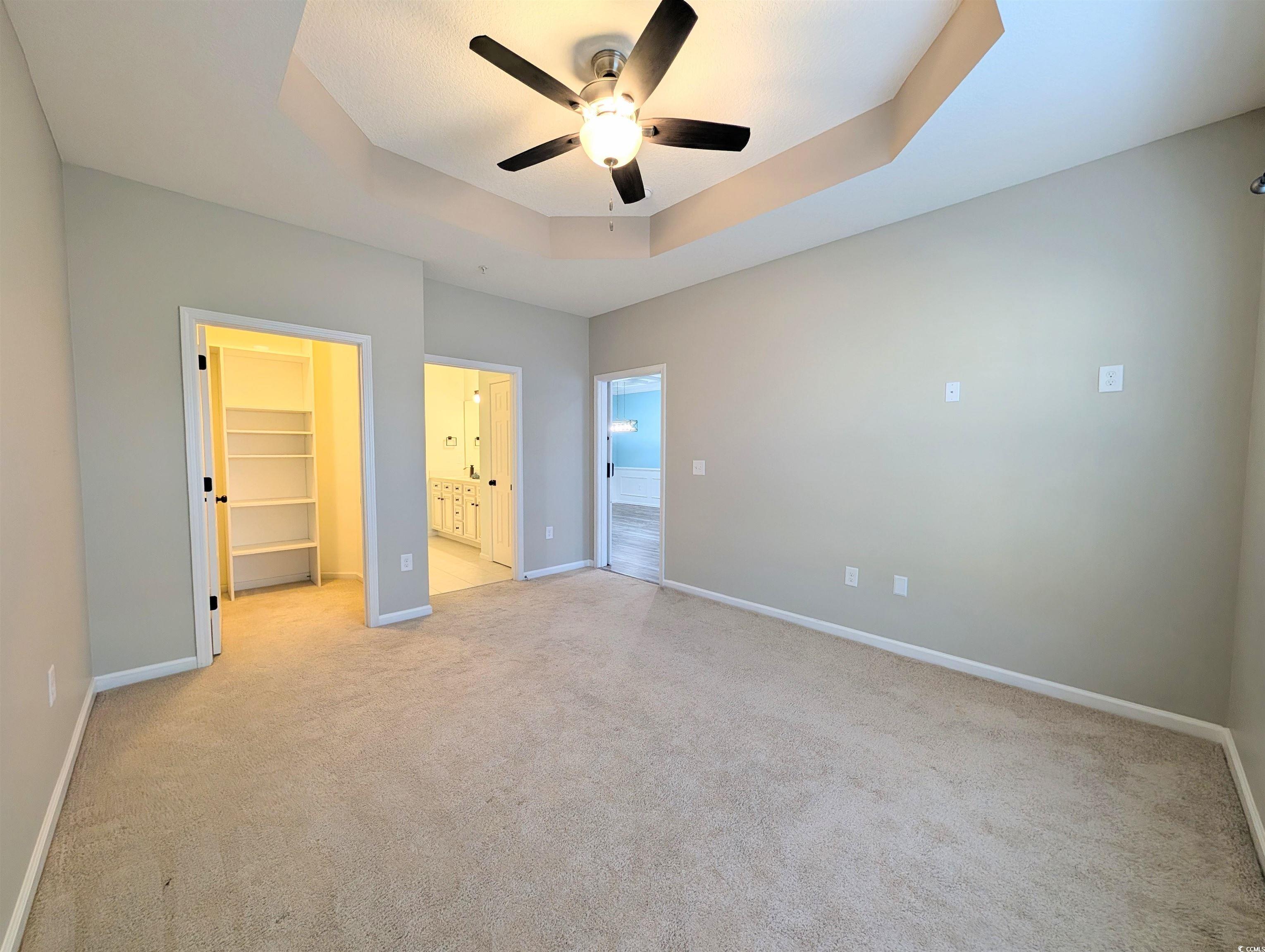822 Sail Lane Murrells Inlet, SC 29576 - Photo 16 of 34 Unfurnished bedroom with a tray ceiling, a spacious closet, carpet flooring, and a ceiling fan