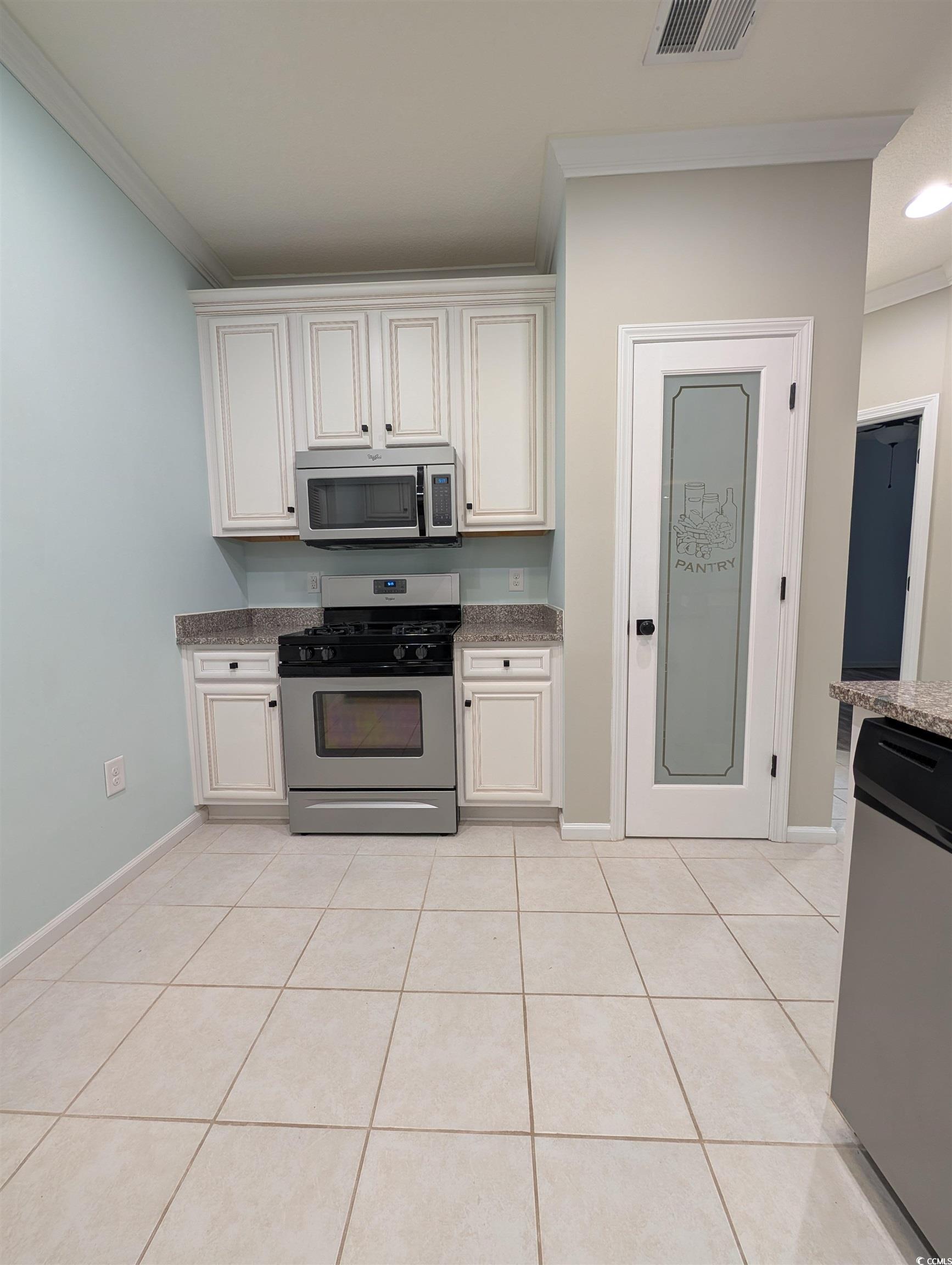 822 Sail Lane Murrells Inlet, SC 29576 - Photo 6 of 34 Kitchen with appliances with stainless steel finishes, crown molding, white cabinetry, light tile patterned floors, and light stone counters