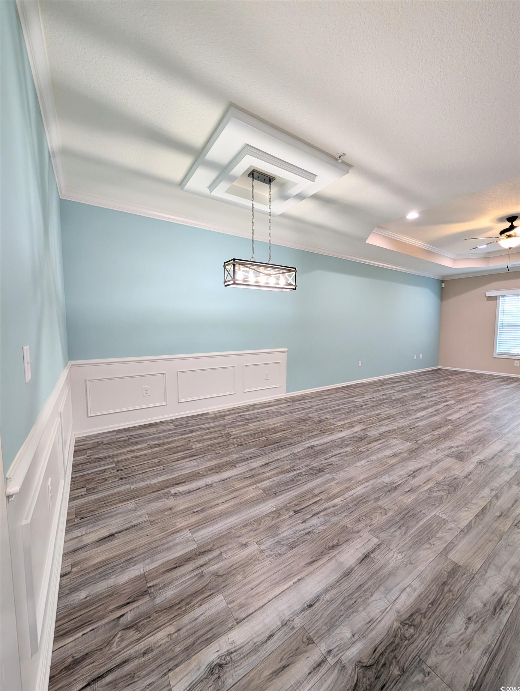 822 Sail Lane Murrells Inlet, SC 29576 - Photo 10 of 34 Unfurnished dining area featuring wood finished floors, a decorative wall, ceiling fan, ornamental molding, and wainscoting