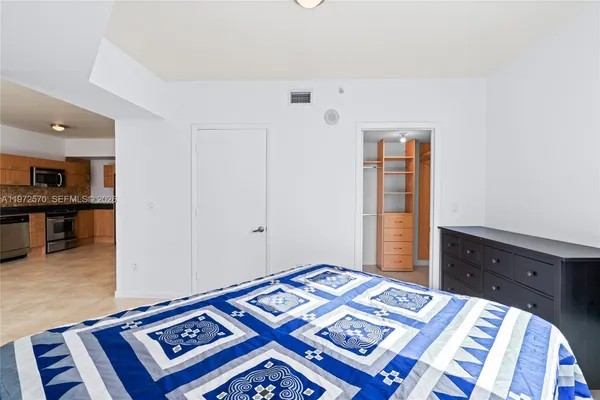 a bedroom with a bed and a lamp on dresser