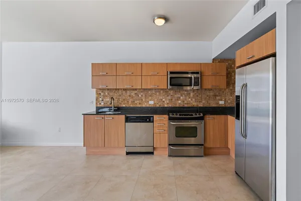 a kitchen with granite countertop a stove top oven and refrigerator
