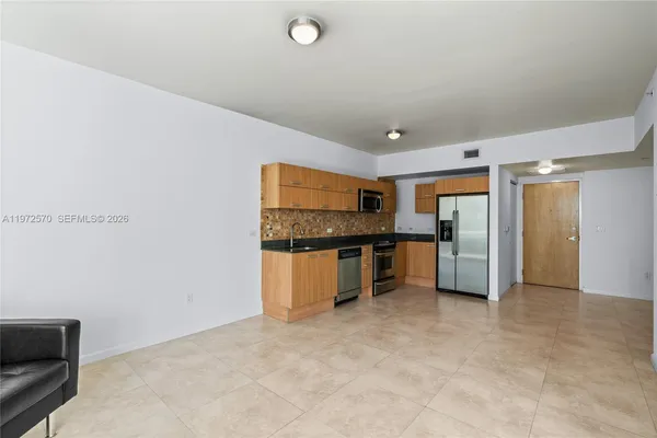 a view of kitchen with refrigerator and white cabinets