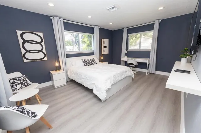 a bedroom with a bed a dresser next to a window