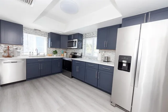 a kitchen with stainless steel appliances granite countertop a refrigerator sink and wooden cabinets