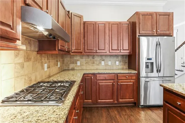 a kitchen with stainless steel appliances granite countertop a sink a stove and a wooden cabinets