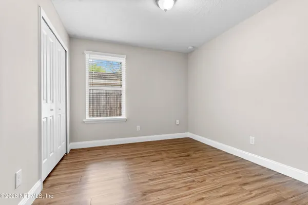 an empty room with wooden floor and windows