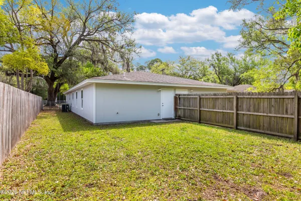 a view of a backyard with a large tree and wooden fence
