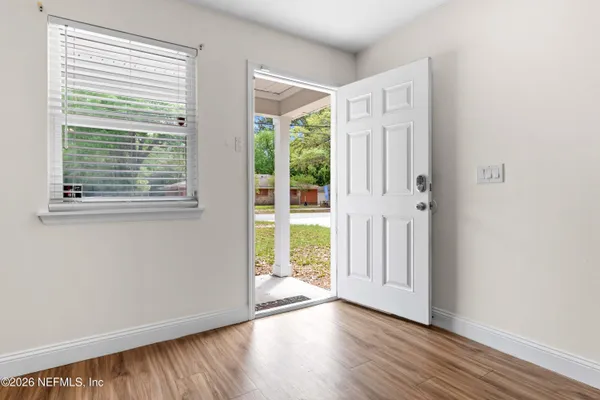 a view of an empty room with wooden floor and a window