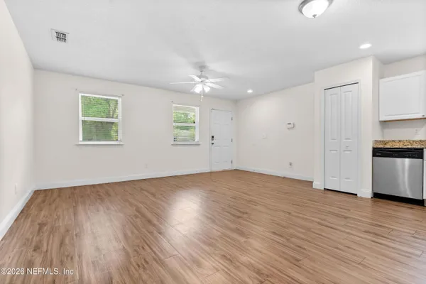 an empty room with wooden floor cabinet and windows