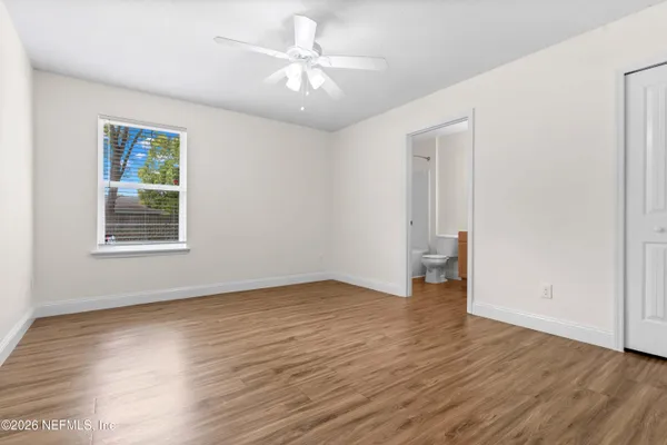 an empty room with wooden floor chandelier fan and windows