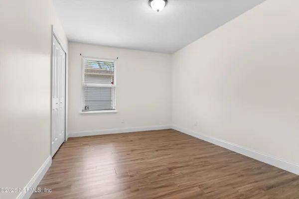 a view of an empty room with wooden floor window