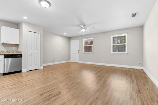 a view of an empty room with wooden floor and a window