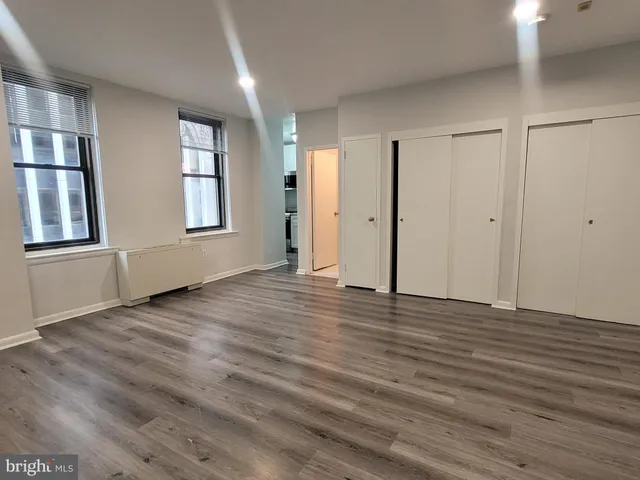 an empty room with wooden floor and windows