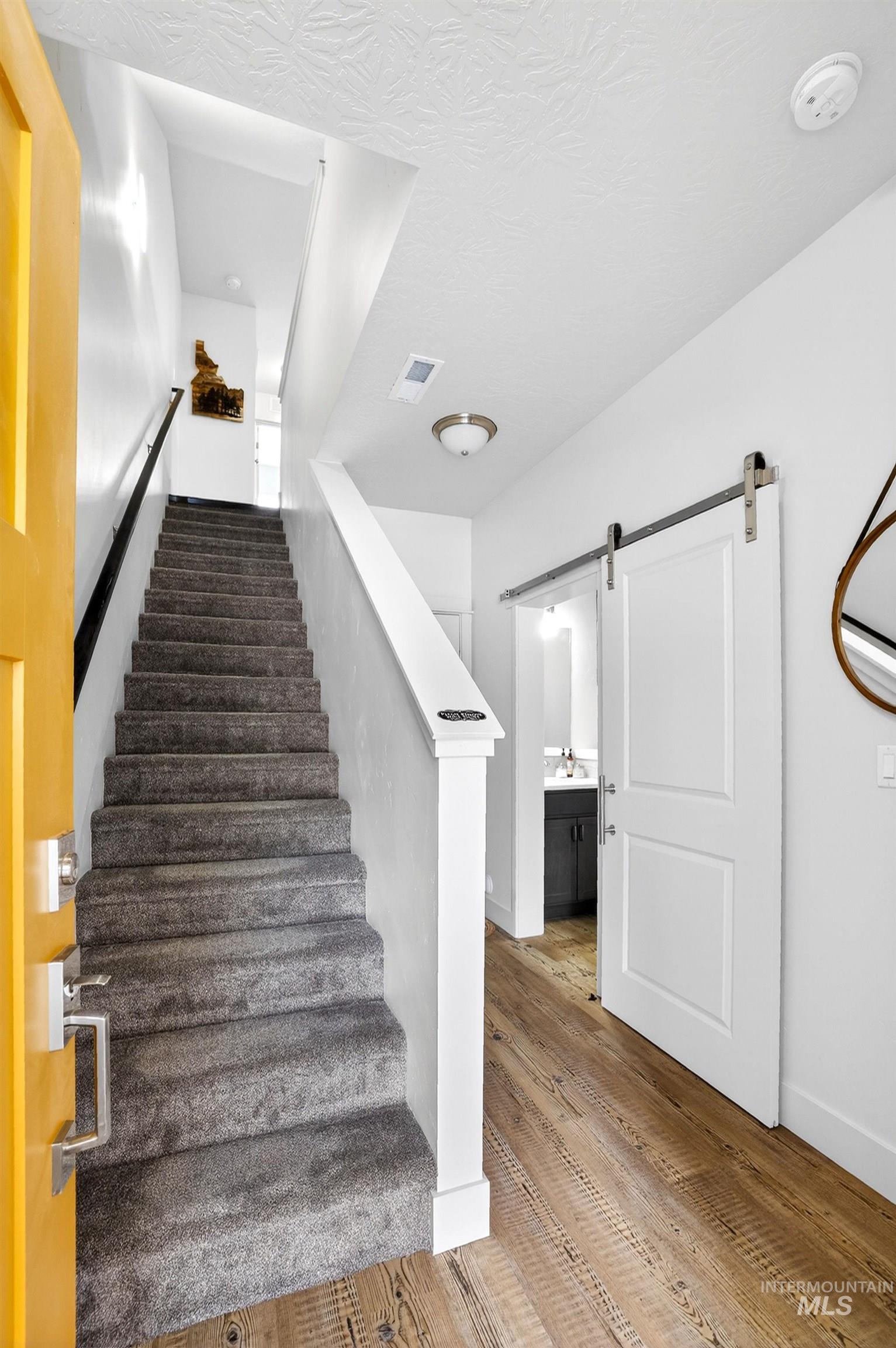311 Broken Ridge Way McCall, ID 83638 - Photo 14 of 44 Entryway featuring wood-finish flooring, a carpeted staircase, and a white barn door