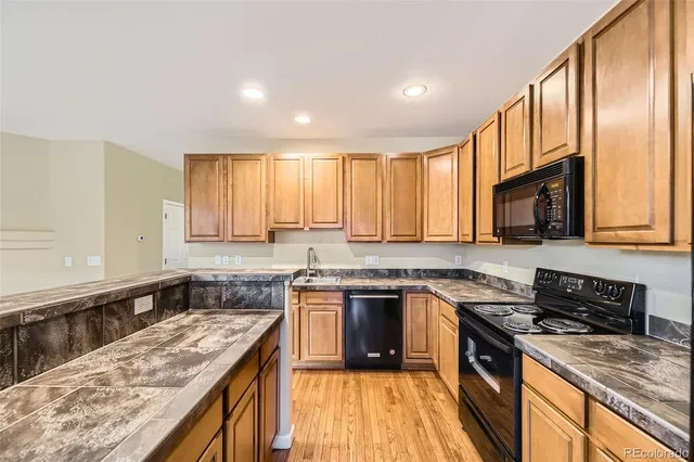 a kitchen with stainless steel appliances granite countertop a stove top oven a sink dishwasher a refrigerator and white cabinets with wooden floor