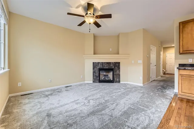 a view of empty room with a fireplace and a ceiling fan