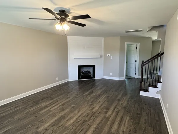 a view of an empty room with wooden floor and a fireplace