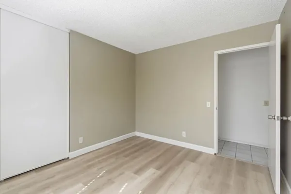 a view of an empty room with wooden floor and closet