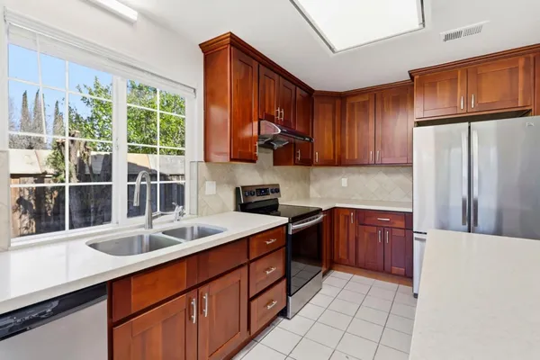 a kitchen with stainless steel appliances granite countertop a refrigerator a sink dishwasher and wooden cabinets with a granite countertops